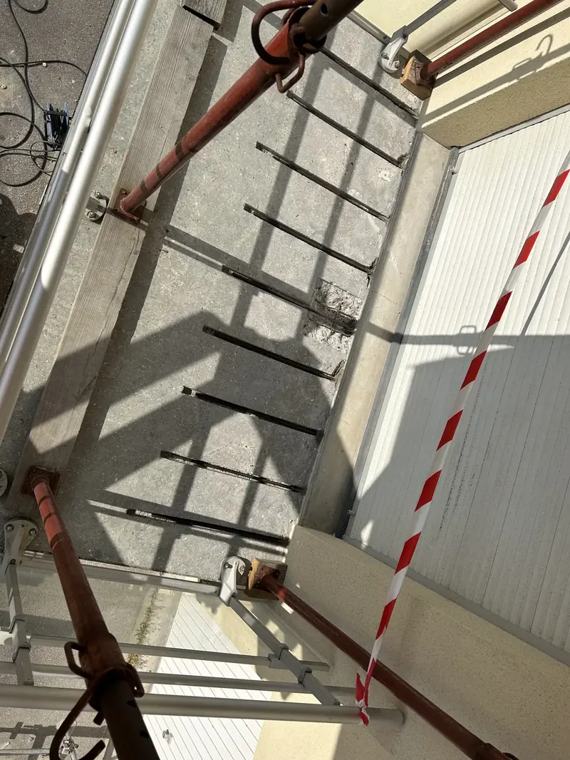 Étais rouges en soutènement contre un mur, zone de chantier balisée