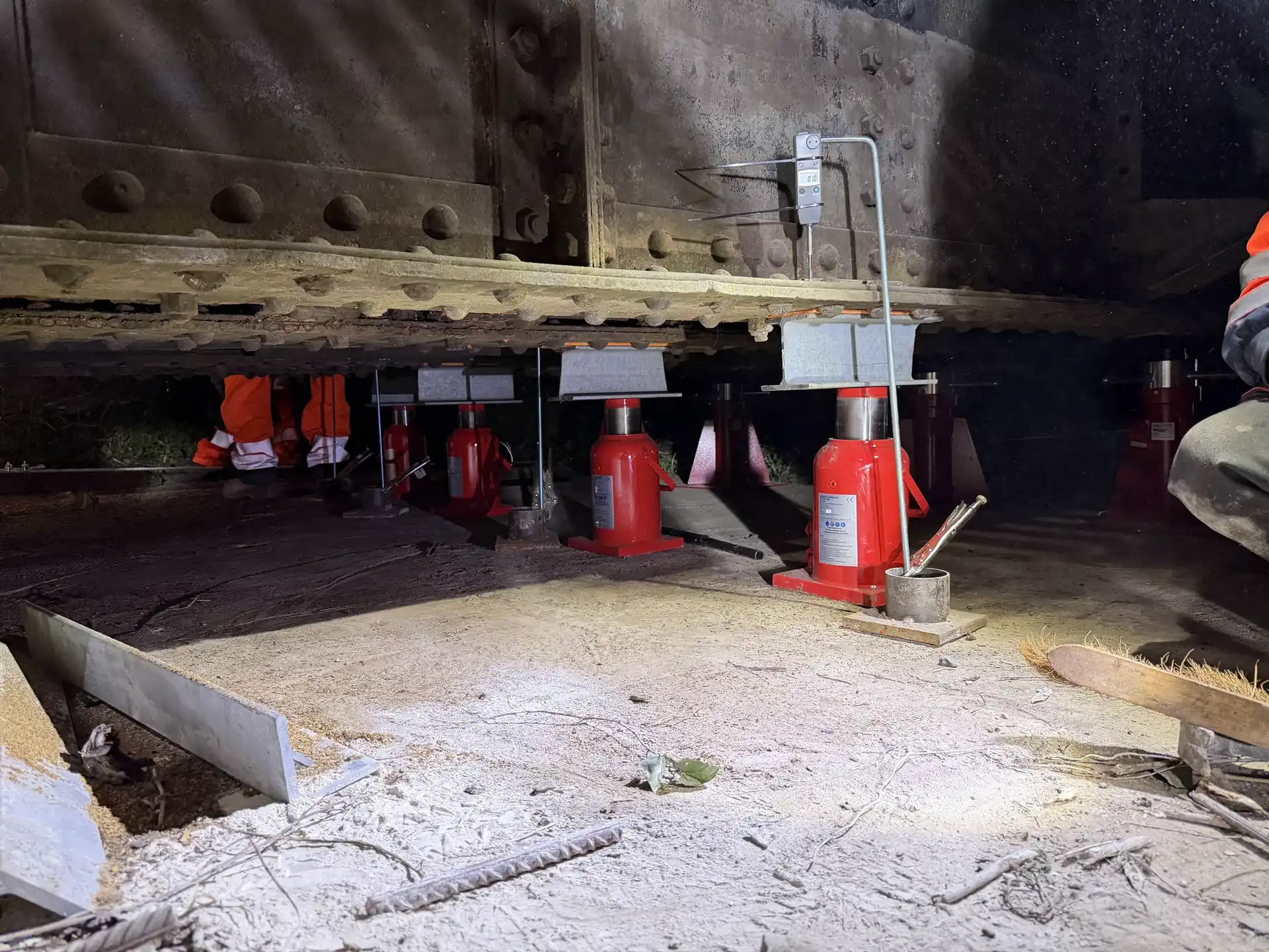 Vérins hydrauliques rouges soutenant une poutre en sous-face lors d'un étaiement